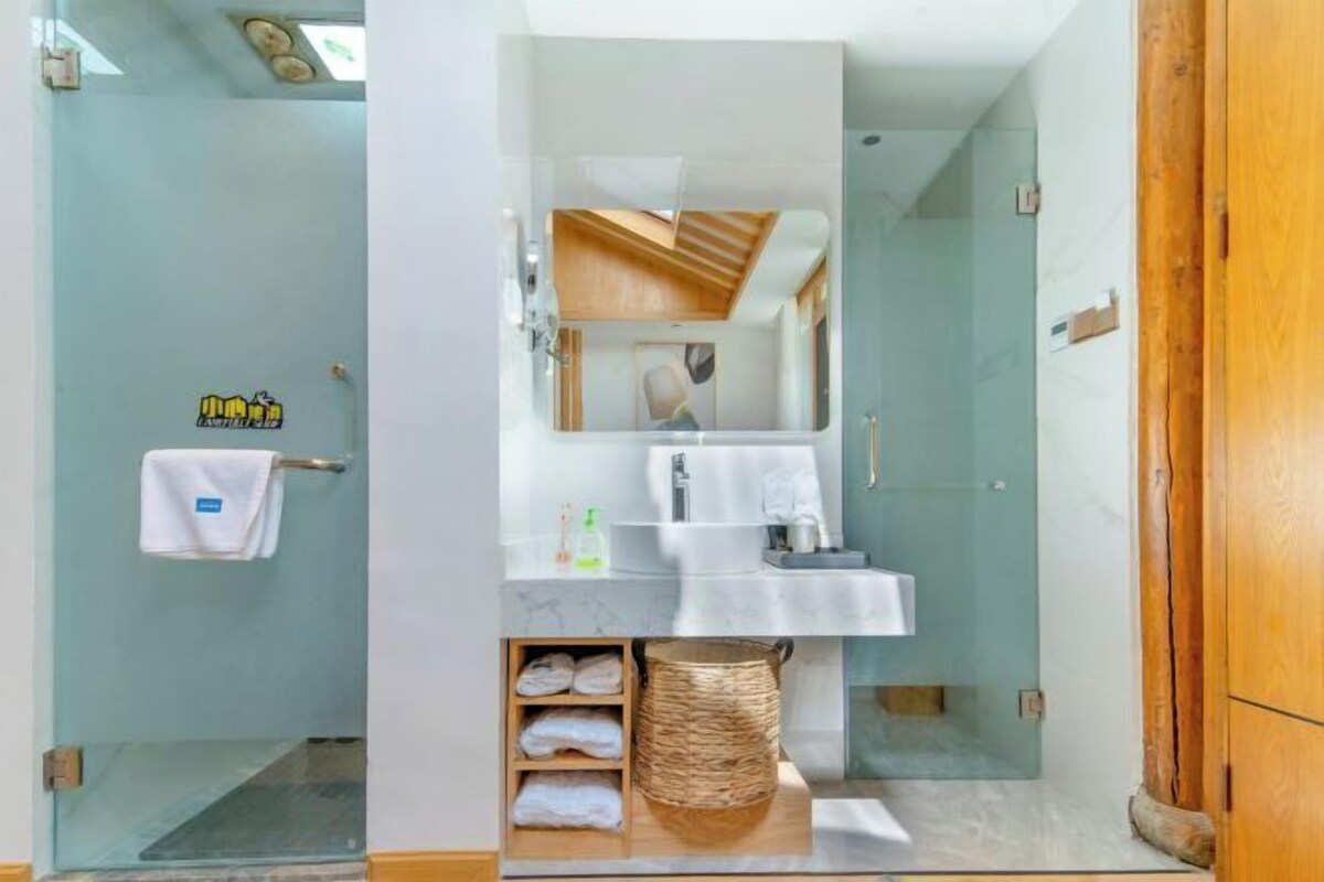 A modern bathroom with a glass shower enclosure, a marble sink, and a wooden vanity.
