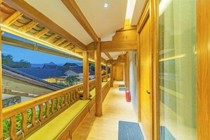 A corridor with wooden railings and benches, leading to a door with a glass panel. - Anju·Rizhao Jinshan Designers' Panoramic Rooftop Cafe and Snow Mountain View (Lijiang)