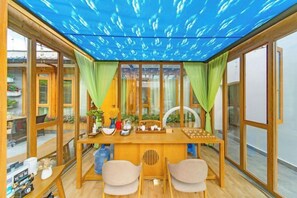 A dining area with a wooden table, chairs, and a view through large windows. - Anju·Rizhao Jinshan Designers' Panoramic Rooftop Cafe and Snow Mountain View (Lijiang)