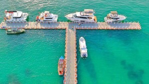 Un muelle con varios barcos amarrados, un paseo marítimo y una lancha en el agua.