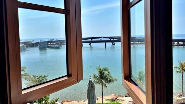 Vista a través de una ventana que muestra una masa de agua con un puente a lo lejos.