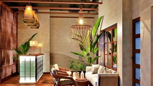 Un hall moderno con piso de madera, un sofá, una silla y una lámpara colgante decorativa.