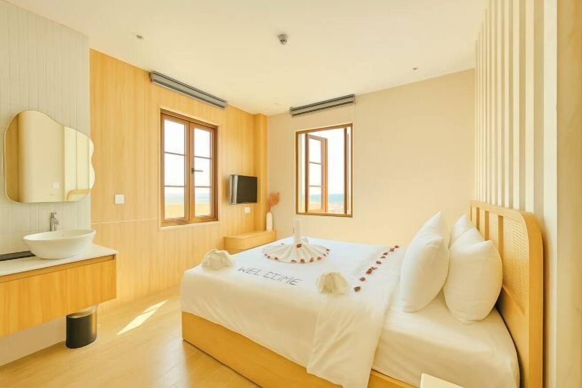 A modern bedroom with a large bed, a bedside table, a TV, and a window with a view.