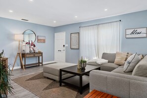 Un salon moderne avec un canapé gris, une table basse, un lampadaire et un miroir décoratif.