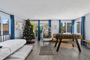 Une pièce chaleureuse avec un lit, un baby-foot, un sapin de Noël et une grande fenêtre.