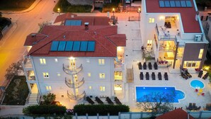 A multi-story hotel with a rooftop pool, outdoor seating, and a well-lit entrance. - Awesome apartment in Fazana with swimming pool (Fazana)