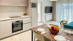 A modern kitchen with a microwave, oven, and sink. There is a dining area with a table set for two, a bowl of fruit, and wine glasses. - Awesome apartment in Fazana with swimming pool (Fazana)