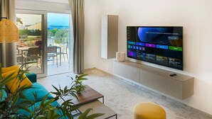 A modern living room with a flat-screen TV mounted on the wall, a sofa, a coffee table, and a balcony with outdoor seating. - 2 bedroom awesome apartment in Fazana (Fazana)