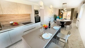 A modern kitchen with a central island, a dining area with a round table, and a view of the outdoors. - 2 bedroom awesome apartment in Fazana (Fazana)