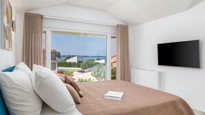 Makuuhuoneessa on suuri sänky, seinälle asennettu televisio sekä näkymä merelle ja kaupungin rakennuksille.