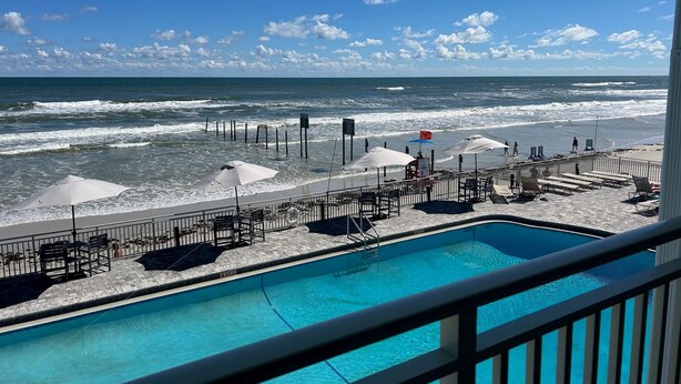 A poolside view with a beach and ocean in the background. - Amazing Beach Location and Ocean View! Unit 220 (Daytona Beach)