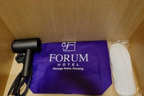 A purple hotel bag with 'FORUM HOTEL George Town, Penang' printed on it, a black hairdryer, and a white object wrapped in plastic. - Forum Hotel Penang (George Town)