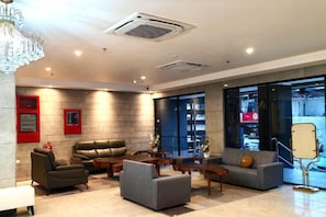 A modern lobby with leather sofas, a coffee table, and a chandelier. - Forum Hotel Penang (George Town)