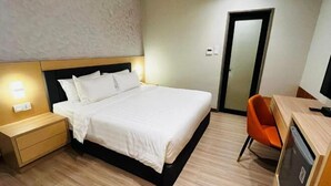 Une chambre d’hôtel comprenant un lit, une table de chevet, une chaise, un bureau et une porte.