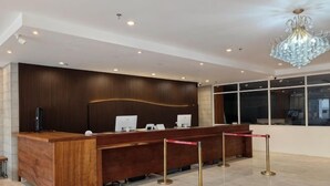 Un comptoir d’accueil avec un revêtement en bois, un lustre et une vue dégagée sur l’extérieur grâce à de grandes fenêtres.