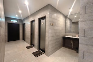 A modern bathroom with a large mirror, a sink, and a shower area. - Forum Hotel Penang (George Town)