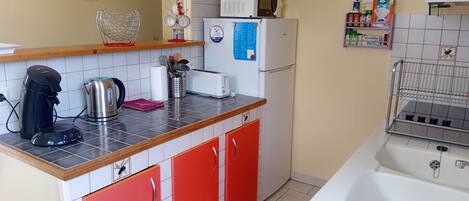 A kitchen with a coffee maker, toaster, microwave, and a refrigerator.
