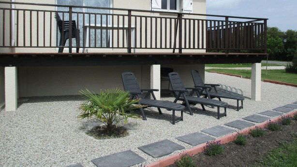 A two-story building with a balcony, outdoor seating area with chairs and a table, and a small palm tree. - T2 48m² Soulac sur mer (Soulac-sur-Mer)