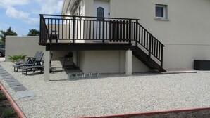 A building with a balcony, outdoor seating, and a gravel ground. - T2 48m² Soulac sur mer (Soulac-sur-Mer)