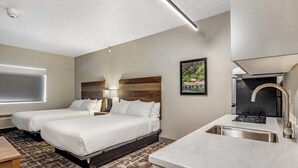 Une chambre d’hôtel avec deux lits, un bureau, un lavabo et une fenêtre.
