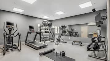 Un gimnasio con cintas de correr, máquinas de pesas y pesas libres.