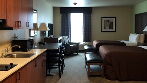 Een compacte hotelkamer met kitchenette, een eethoek, een bank en een bed.