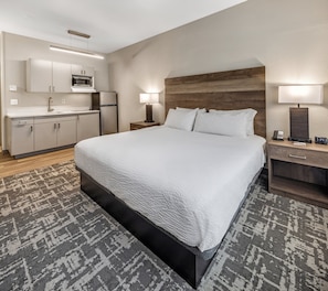 Een hotelkamer met een groot bed, een nachtkastje, een bureau, een magnetron en een koelkast.