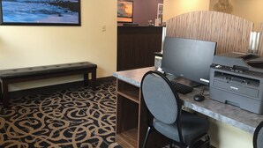 Een hotelkamer met een bureau, computer, printer en een bank.