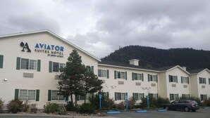 Een gebouw met de tekst 'AVIATOR SUITES HOTEL', met een bergachtige achtergrond.