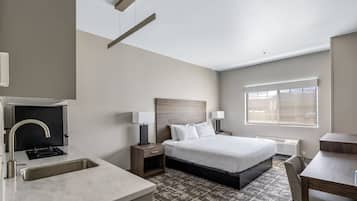 Habitación de hotel con cama, mesitas de noche, escritorio, ventana y baño con lavabo y espejo.