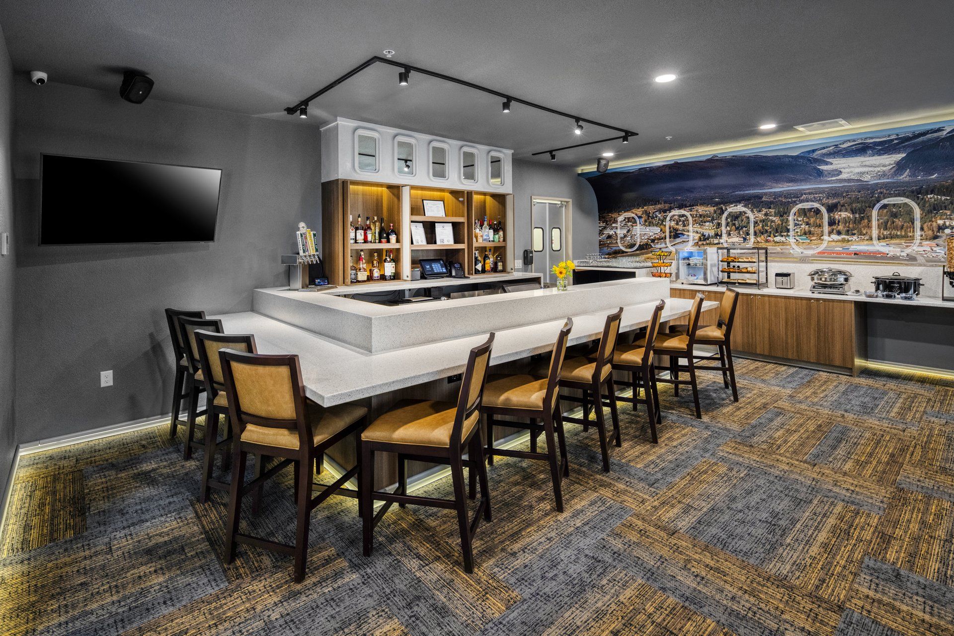 A bar area with a long counter, multiple stools, and a view of a snowy landscape through a window.