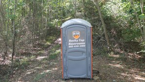 A portable restroom labeled "Rocky Top Restrooms" with a phone number.