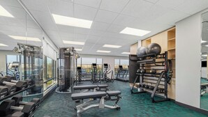 Un gimnasio con equipamiento de ejercicio, bancos y un espejo grande.