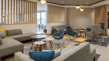 A modern lounge area with sofas, armchairs, and tables, featuring a neutral color palette and natural light.