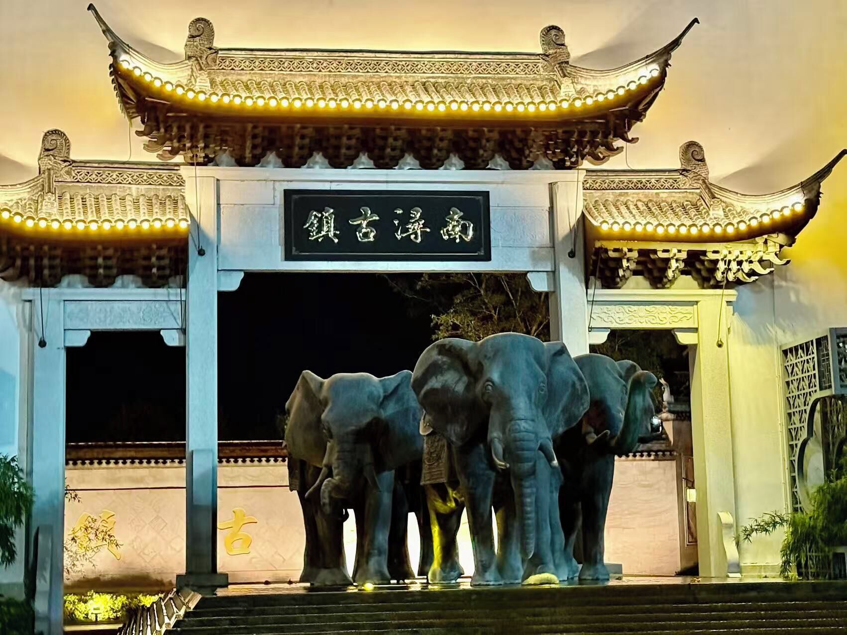 A traditional Chinese gate with a sign, flanked by two elephant statues.