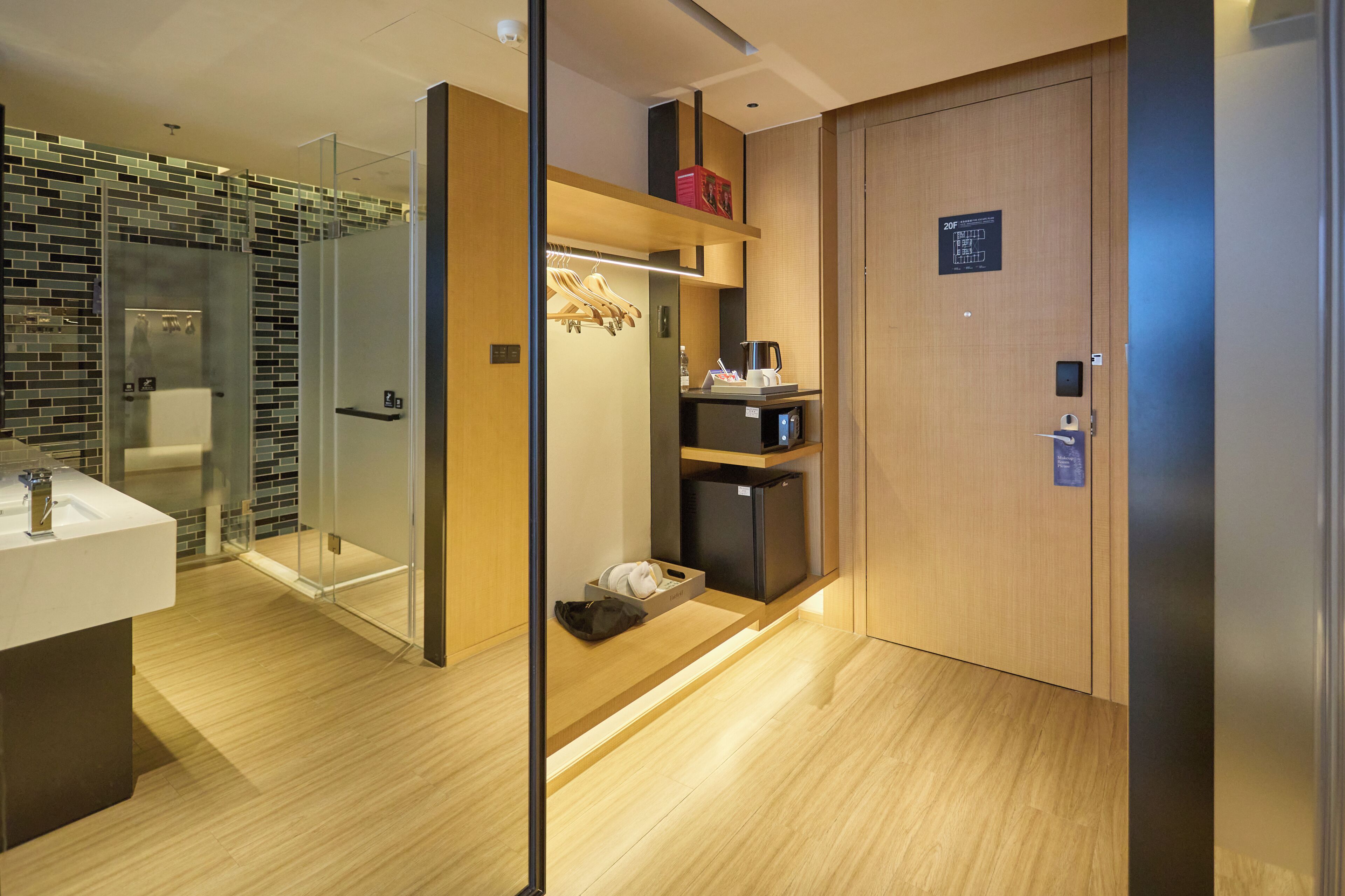 A modern bathroom with a glass shower enclosure, a wooden vanity, and a built-in coffee machine.