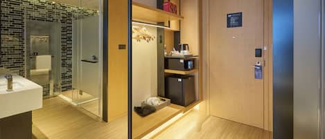 A modern bathroom with a glass shower enclosure, a wooden vanity, and a built-in coffee machine.
