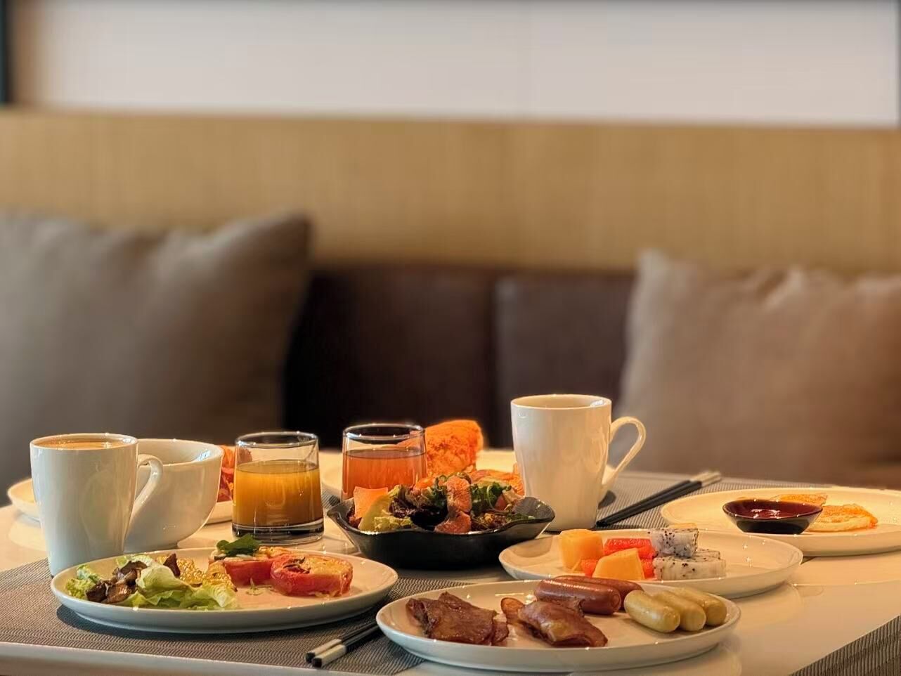 A breakfast setting with coffee, tea, and various dishes on a table.