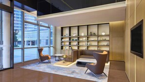 A modern lobby with a sofa, chairs, a coffee table, a bookshelf, and a TV. - Fairfield By Marriott Huzhou Nanxun (Huzhou)