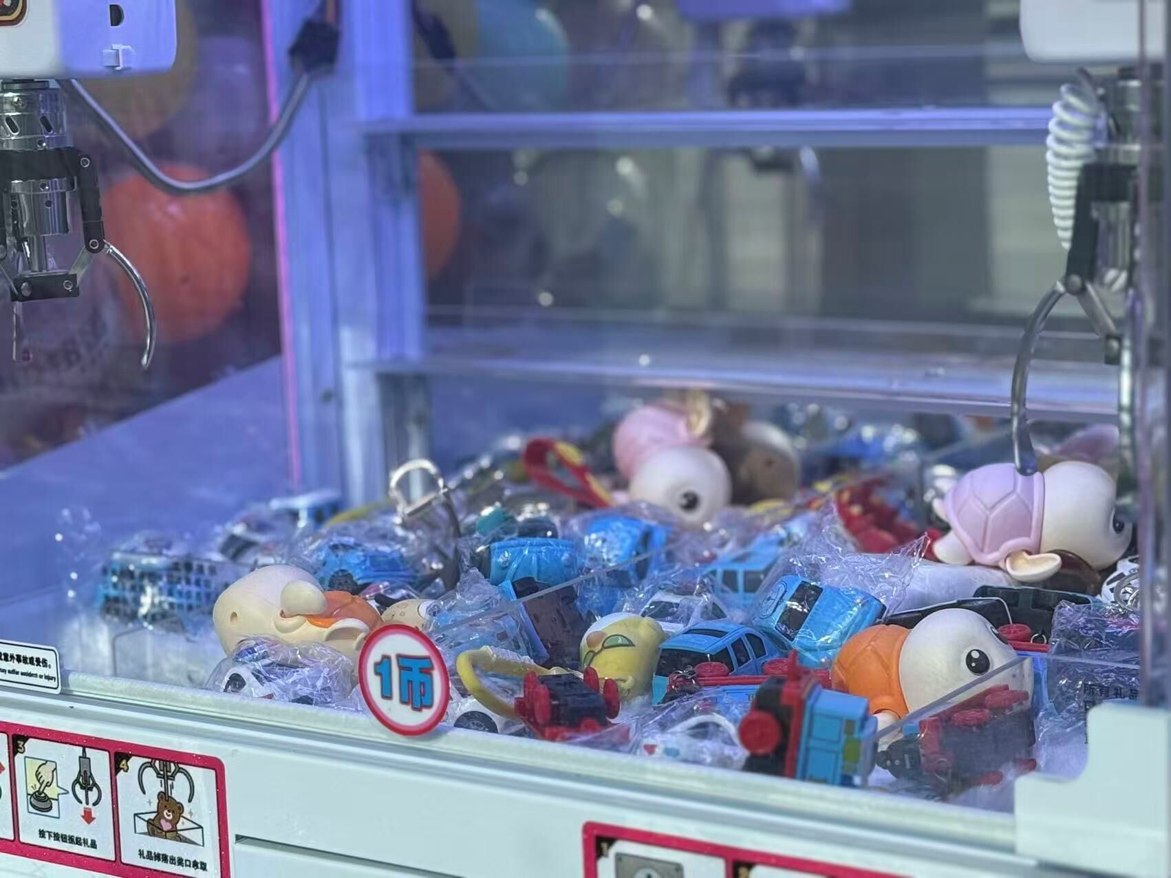 A claw machine filled with various toys and items, including a bear and a pink character.