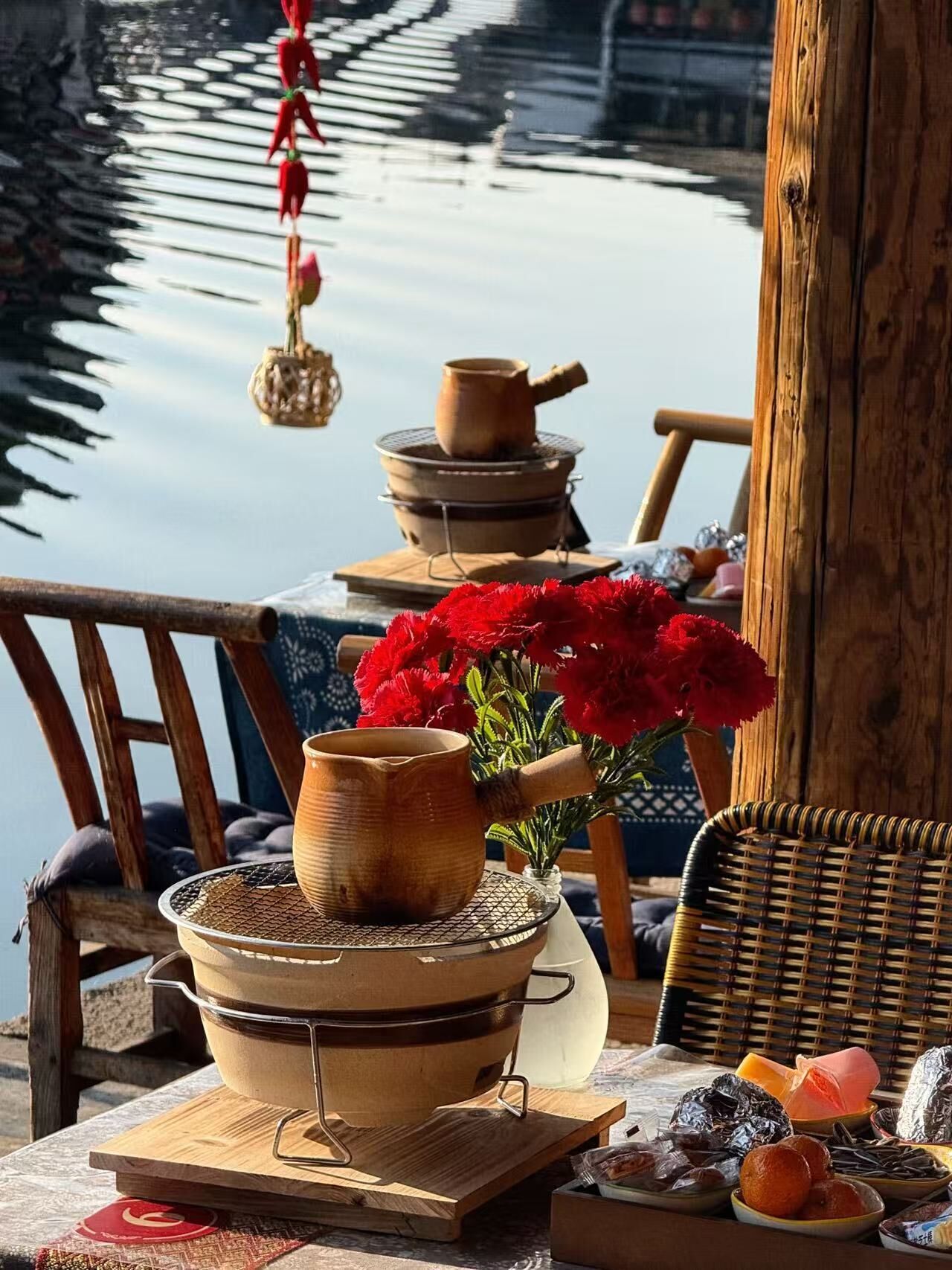 A rustic outdoor setting with a wooden table, a traditional tea set, and a wicker chair.