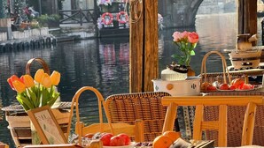 A riverside table setting with tulips, a basket, a teapot, and a wooden chair. - Fairfield By Marriott Huzhou Nanxun (Huzhou)