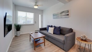 A modern living room with a grey sofa, a wooden coffee table, and a ceiling fan. - Updated 1BR in Point Loma – Near Harbor & Airport (San Diego)
