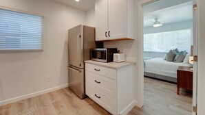 A compact kitchen with a refrigerator, microwave, and toaster, and a bedroom with a bed and bedside table. - Updated 1BR in Point Loma – Near Harbor & Airport (San Diego)