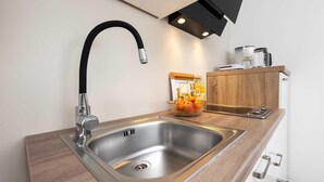 Una cocina moderna con un lavamanos de acero inoxidable, un grifo negro y una encimera de madera.