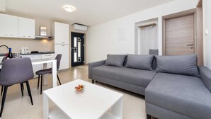 En modern lägenhet med en grå soffa, ett vitt soffbord och en matplats med ett vitt bord och stolar.