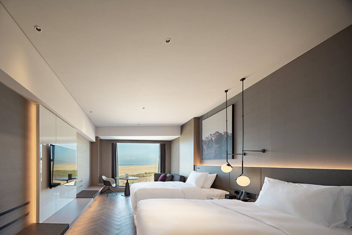 Una habitación de hotel moderna con una cama grande, un televisor, un escritorio y vistas al paisaje.