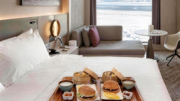 Una habitación de hotel con una cama, una mesita de noche con lámpara, una pequeña mesa redonda y un sofá.