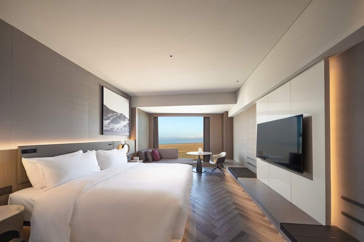 Habitación de hotel moderna con una cama grande, televisión y vistas al océano.
