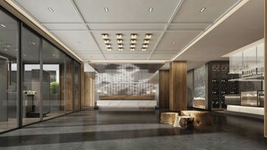 Un vestíbulo moderno con un muro de cristal, un mostrador de recepción y una exhibición de vinos.
